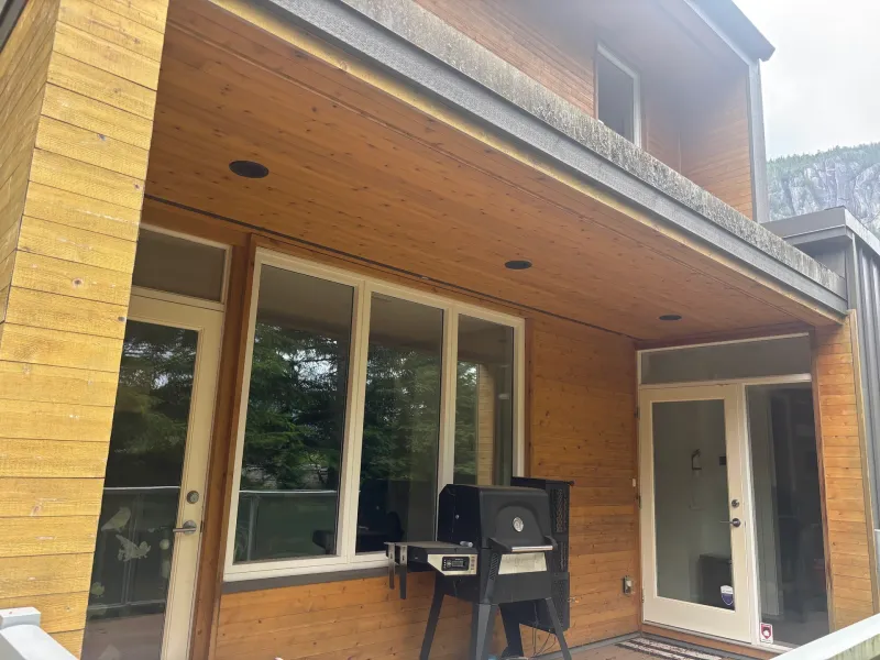 After: Covered patio with siding walls, windows, and glass doors beneath upper level wall, . Arbour woods, Squamish, BC
