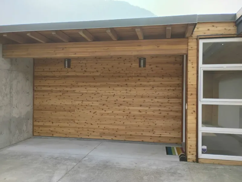 Before: Garage door with siding trim and adjacent window wall on the front of the house, . Arbour woods, Squamish, BC