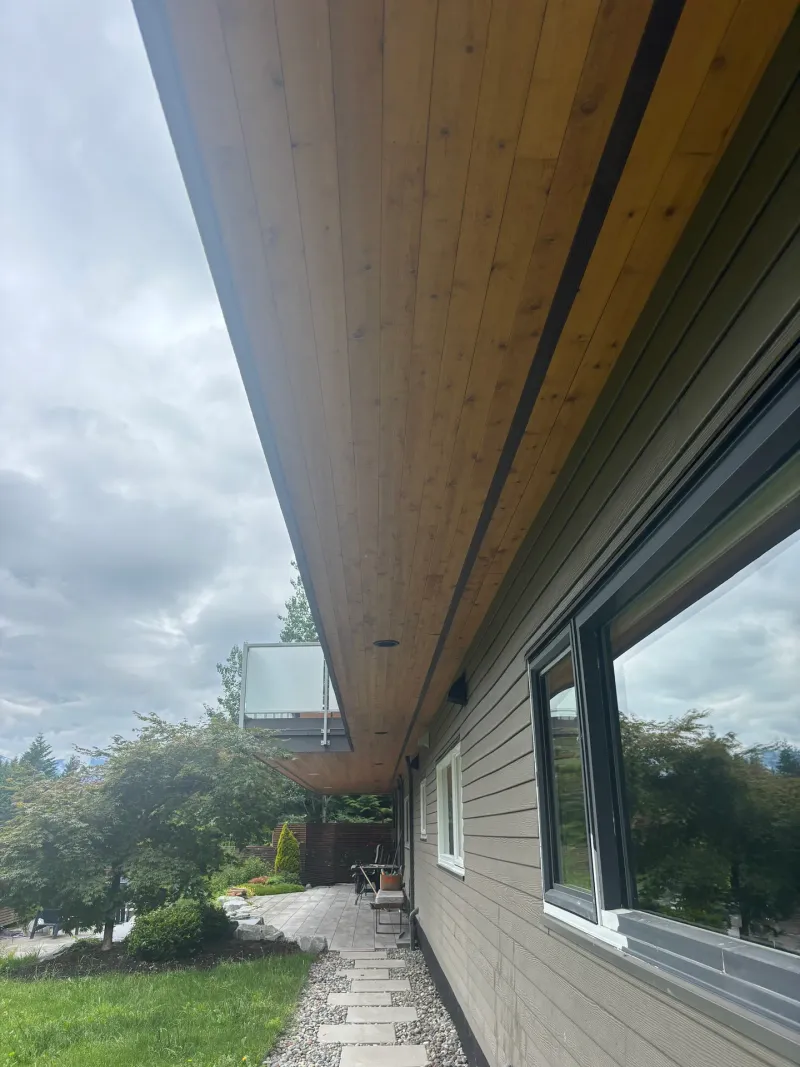 Before: View along underside of soffit and eave with siding wall and windows below, . Arbour woods, Squamish, BC