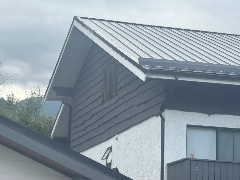 After: Upper gable corner showing dark siding over white wall with a window, Brackendale, Squamish, BC