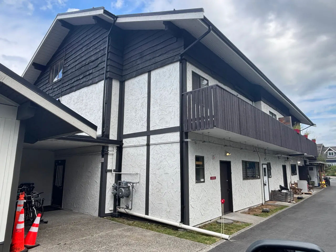 After: Wide side elevation of building with upper balcony, white walls and dark trim and siding, Brackendale, Squamish, BC