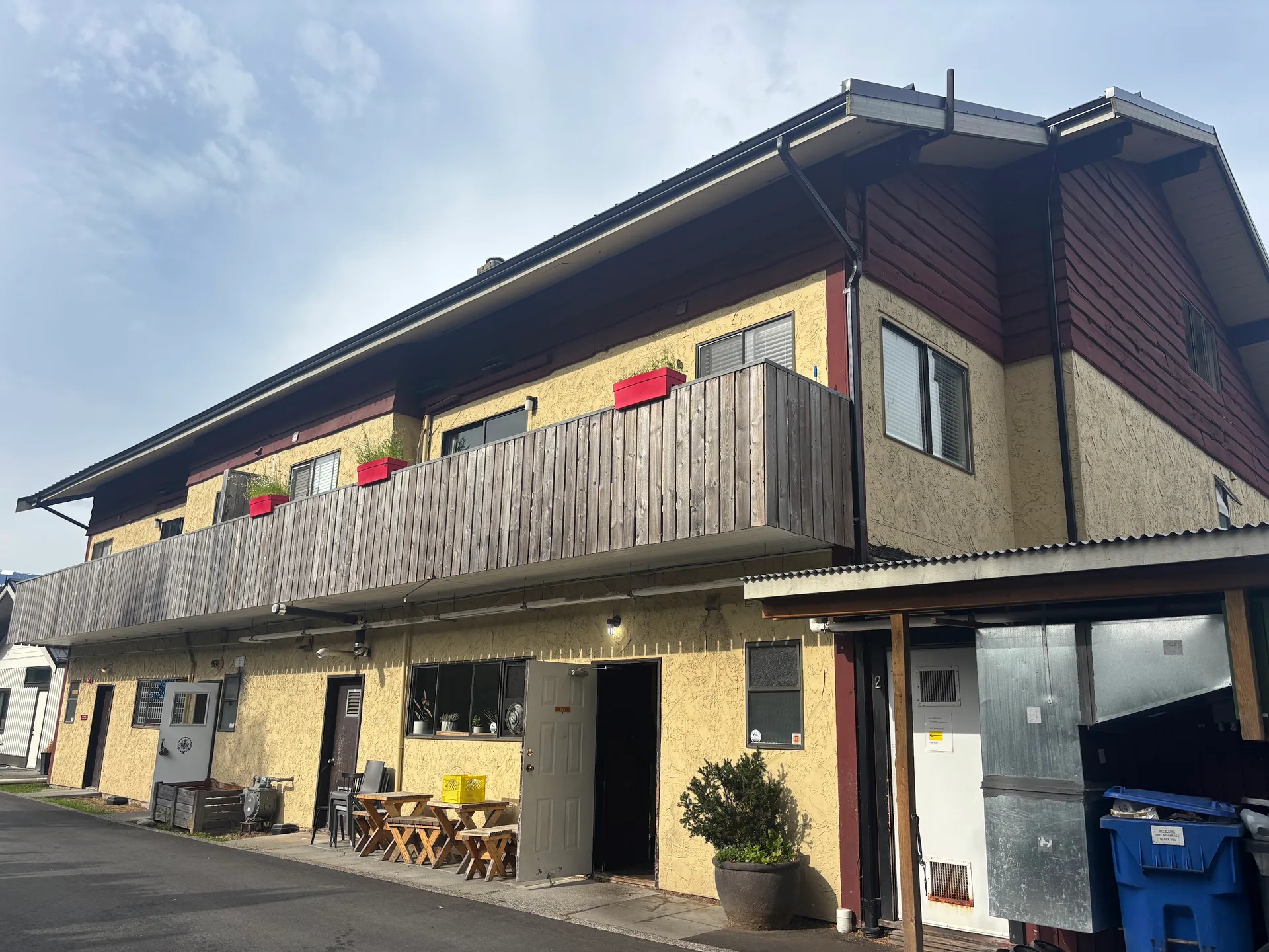 Before: Wide side elevation of building with upper balcony, and siding walls, and doors below, Brackendale, Squamish, BC