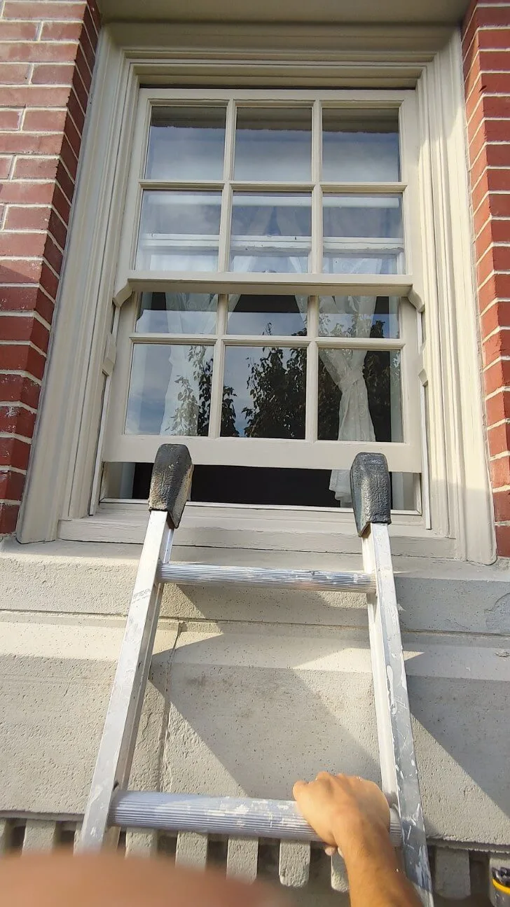 After: Front window with freshly painted trim and sash, ladder resting against sill, Central - Granville St, Vancouver, BC