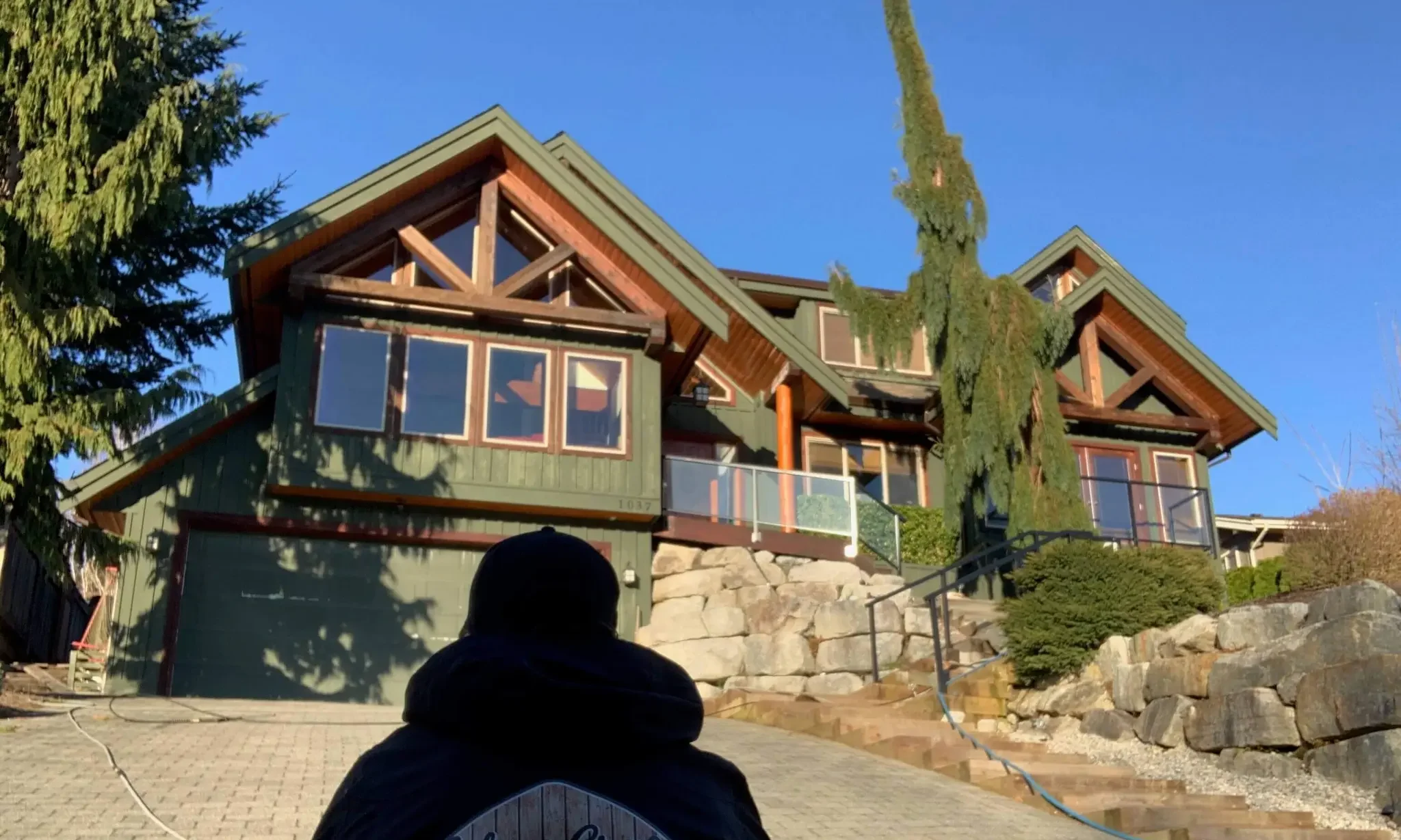 Colour Craft painter viewing a green craftsman home for exterior colour inspiration