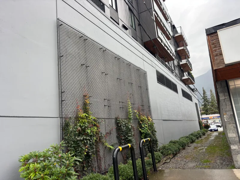After: Side elevation of freshly painted wall with protective screen and bike racks along walkway, Downtown, Squamish, BC