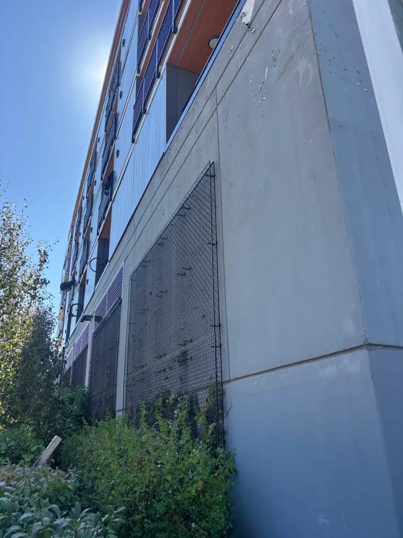 Before: Upward angled view of side elevation with protective screen below balconies, Downtown, Squamish, BC