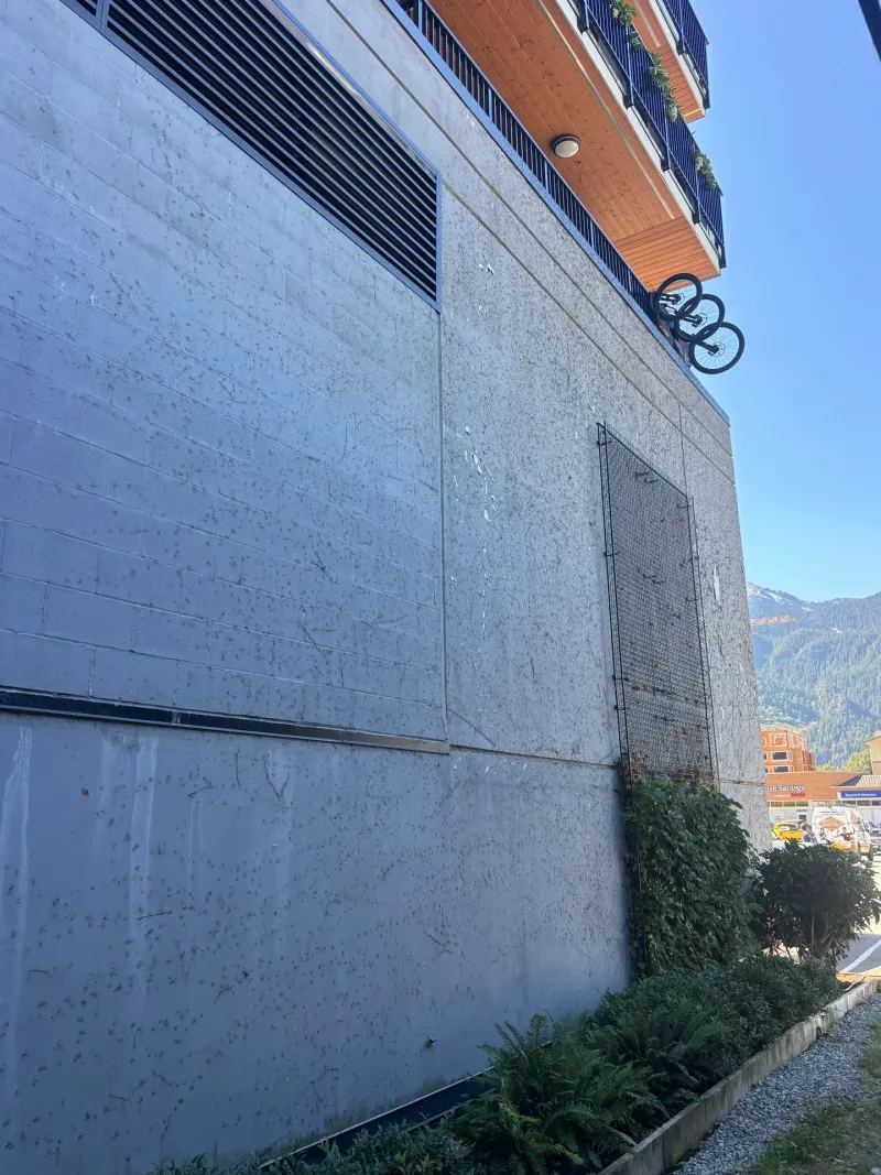 Before: Upward angled view of side elevation wall with protective screen, Downtown, Squamish, BC