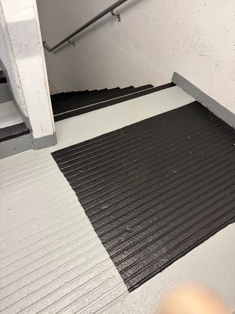 After: Newly coated landing with dark textured nonslip surface and light gray steps beyond, Downtown, Squamish, BC