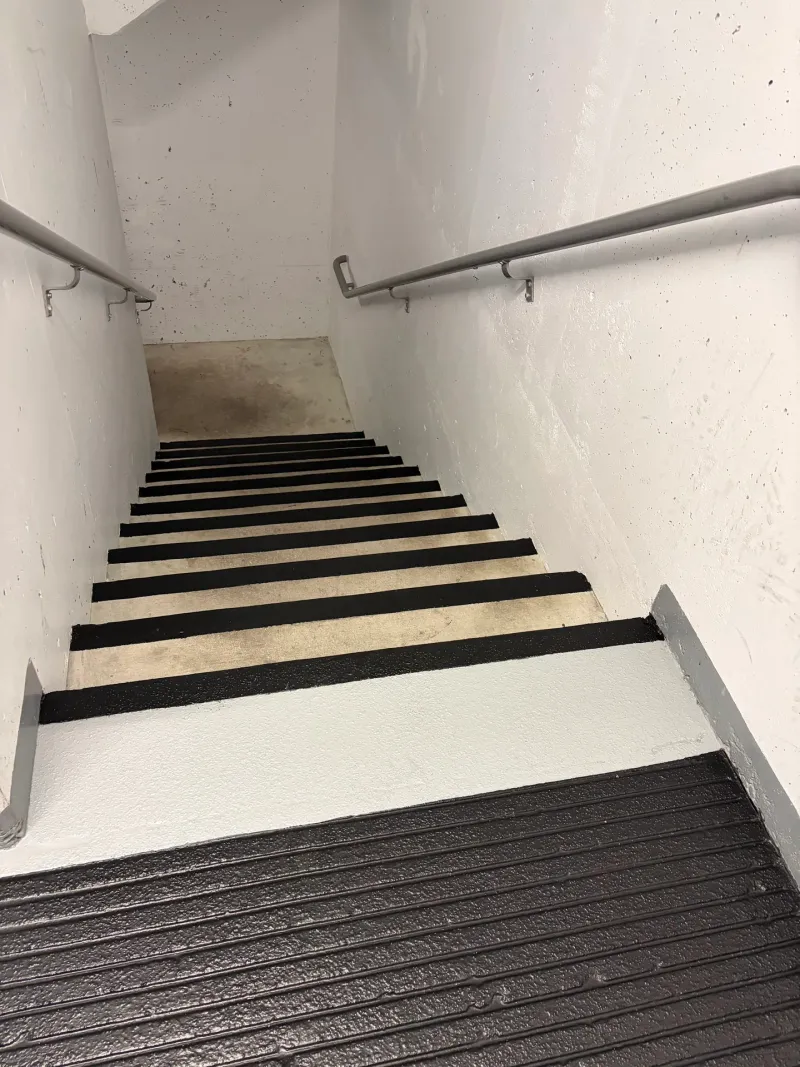 After: Interior stairwell with freshly painted black-and-white stair treads descending to a landing, Downtown, Squamish, BC