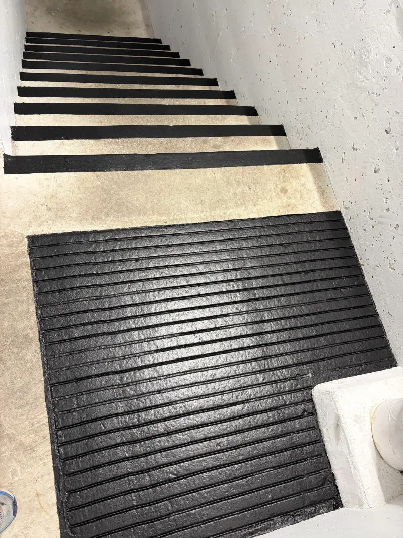 After: Stairwell with newly coated dark stair treads transitioning to unfinished concrete, Downtown, Squamish, BC