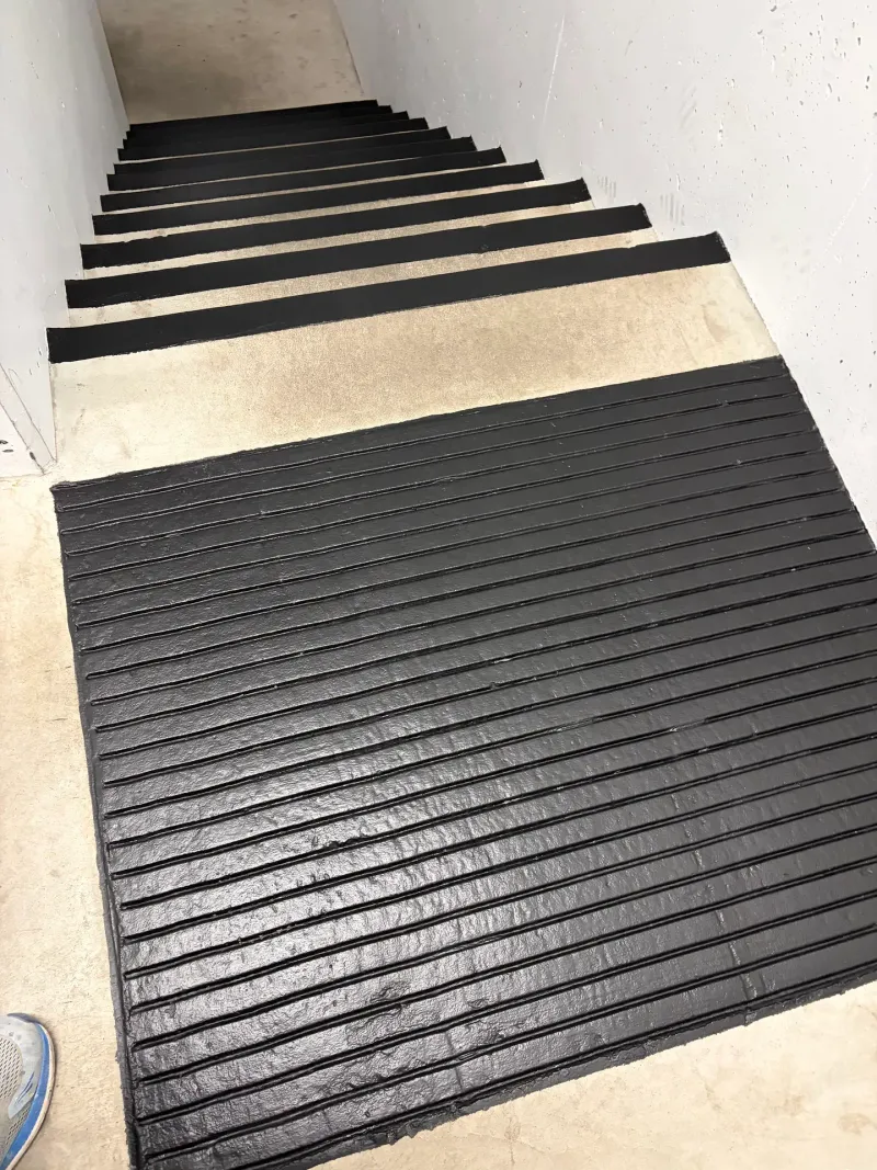 After: Stairwell with newly coated dark stair treads transitioning to unfinished concrete, Downtown, Squamish, BC
