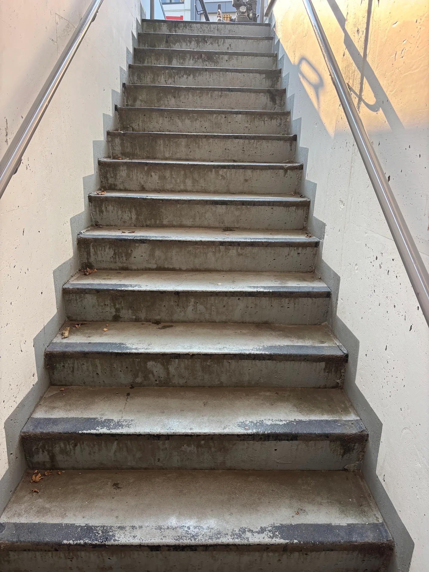 Before: Concrete stairwell viewed from the bottom looking up at worn stair treads and side walls, Downtown, Squamish, BC