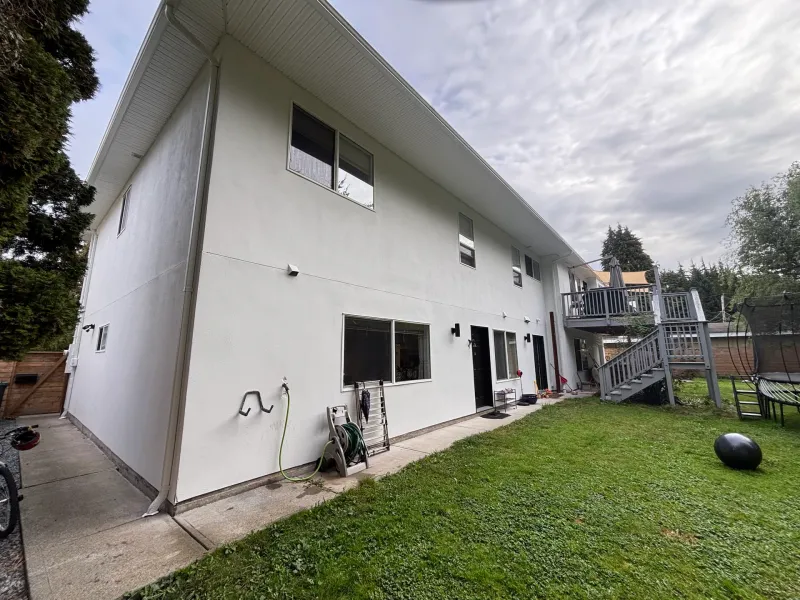 After: Rear elevation of a house with multiple windows, two doors, and an exterior staircase leading to an upper deck, Garibaldi highlands, Squamish, BC