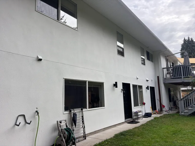 After: Angled rear view of a house with multiple windows, two doors, and a deck in the background, Garibaldi highlands, Squamish, BC