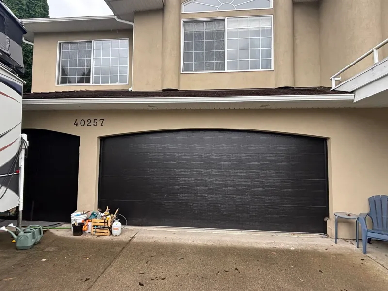 Before: Close view of a double garage door and upper story windows on the front of a house, Garibaldi highlands, Squamish, BC