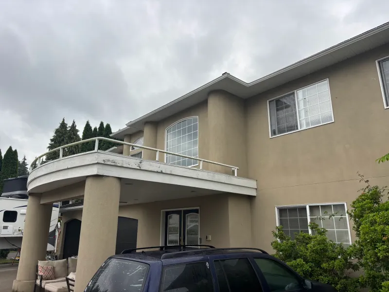 Before: Angled view of a house front showing a curved balcony, upper windows, and covered entry roof, Garibaldi highlands, Squamish, BC