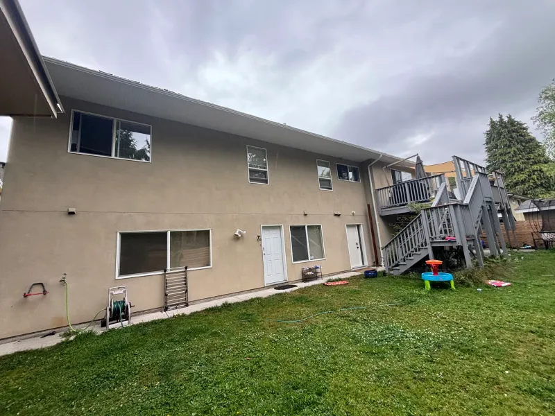 Before: Rear elevation of a house with multiple windows, two doors, and an exterior staircase leading to an upper deck, Garibaldi highlands, Squamish, BC