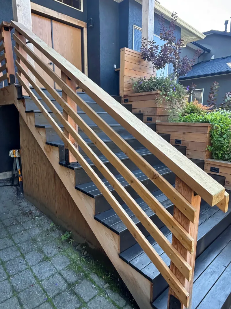 After: Side view of staircase with dark painted treads and a slat railing along the house wall, Highlands, Squamish, BC