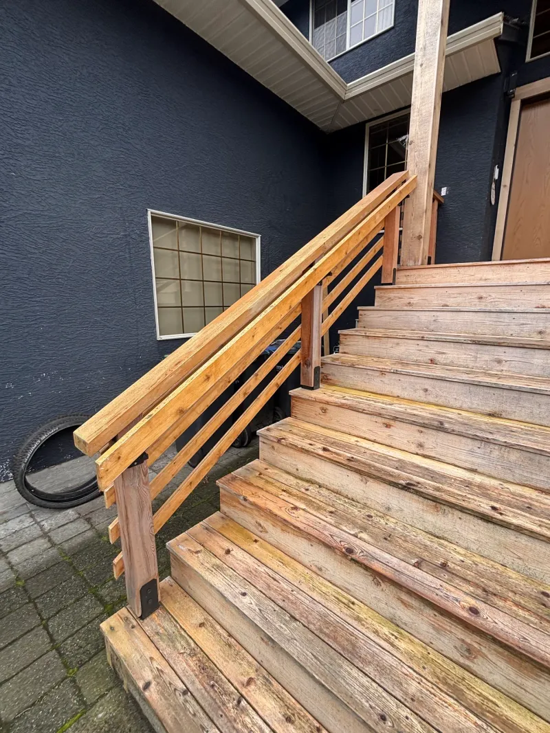 Before: Side view of unpainted staircase and railing along the house wall with a window above, Highlands, Squamish, BC