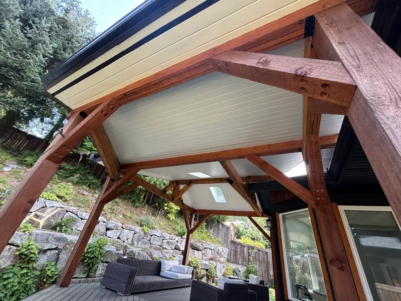After: Painted white patio ceiling with dark beams above an outdoor seating area, - Isabella Rd, Salt Spring Island, BC