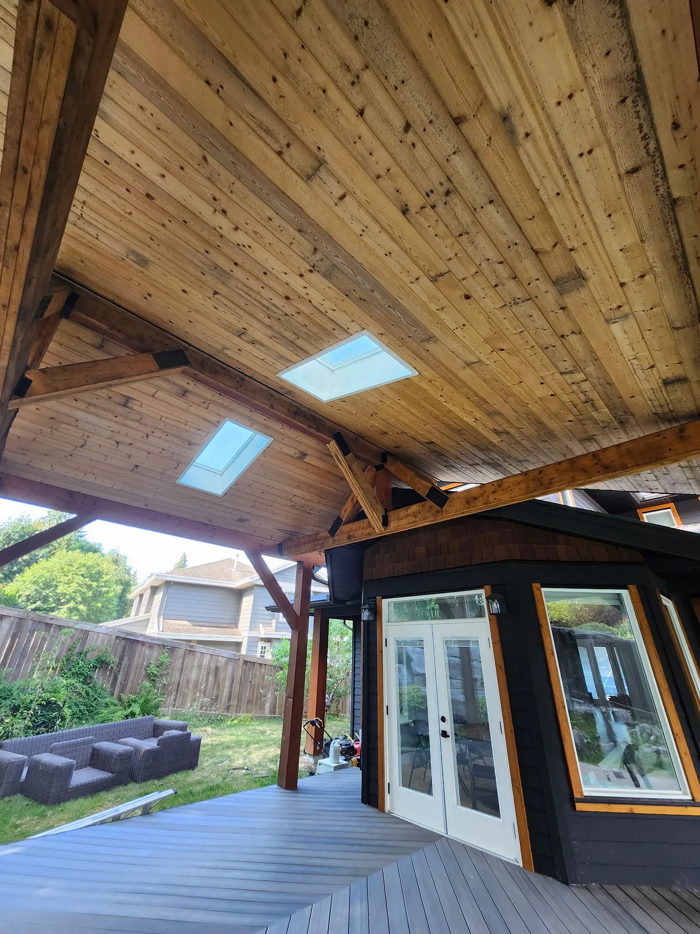 Before: Underside of a covered patio roof with exposed ceiling and beams above a rear patio door, - Isabella Rd, Salt Spring Island, BC