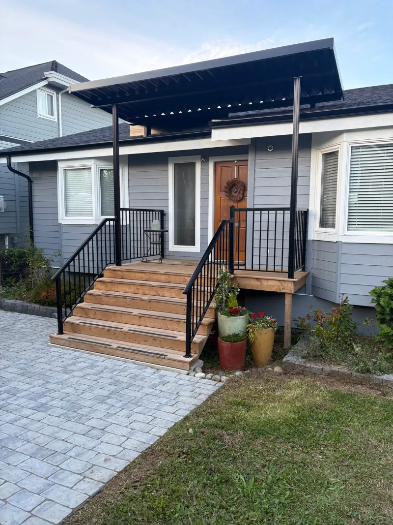 After: Front elevation of house with covered entry porch, steps, black railings, door, and windows, New Westminster, BC