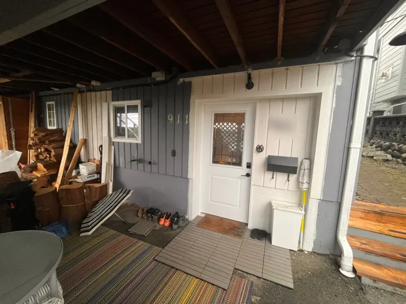 Before: Covered side entry with door, siding, and trim under a deck, New Westminster, BC