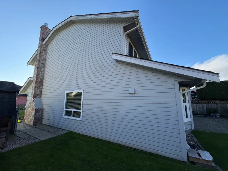 Before: Side elevation showing tall gable, chimney, and single window above patio, Richmond, BC
