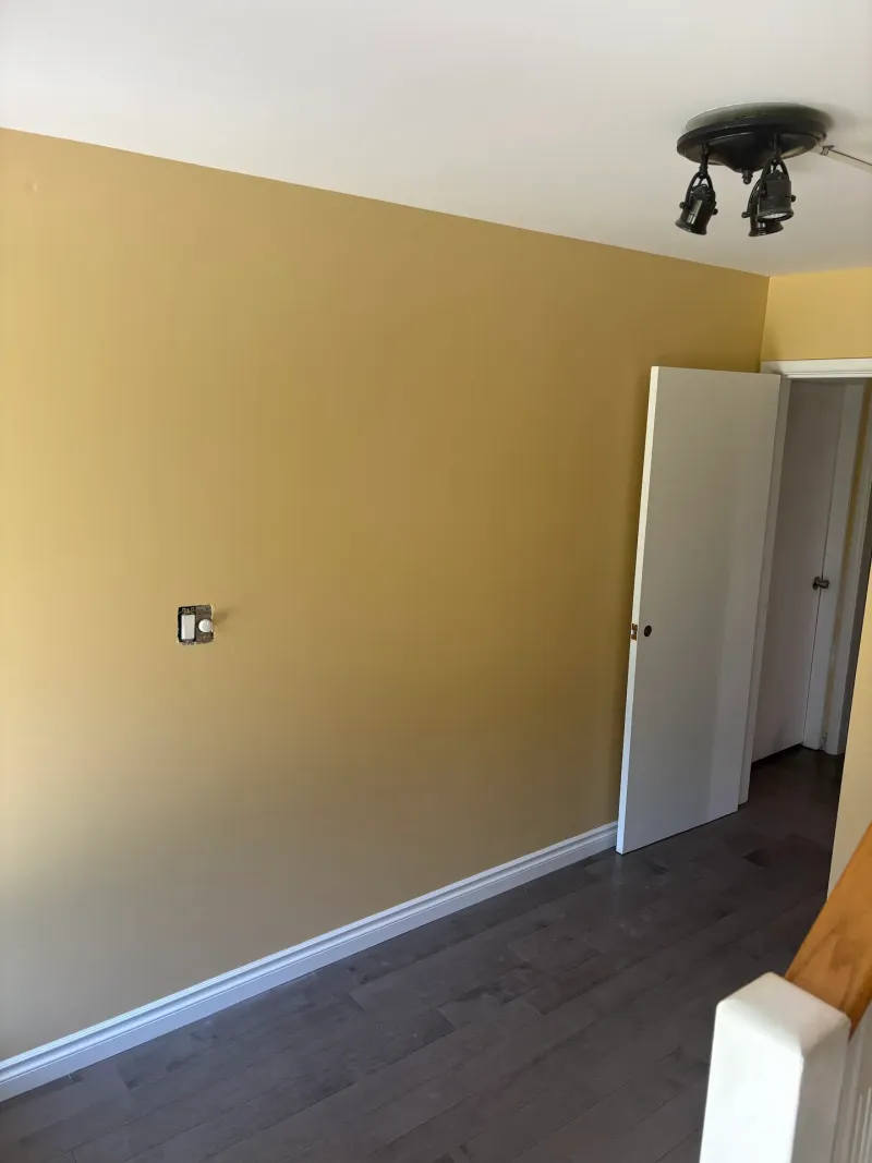 After: Bedroom wall with door opening to hallway and staircase railing, Seafair, Richmond, BC