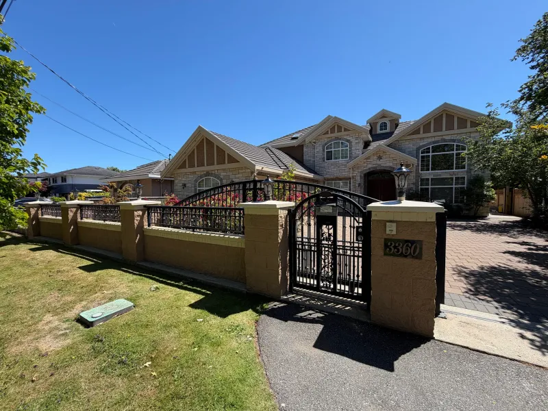 After: Front yard fence, iron gate and stone pillars with house visible behind, Seafair, Richmond, BC