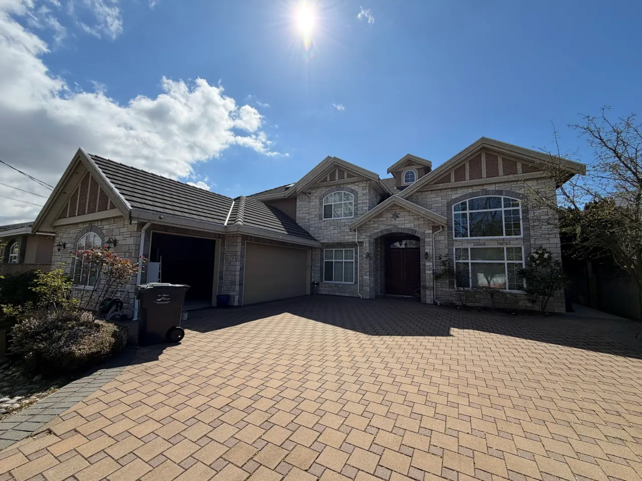 Before: Front elevation of two-story house with stone facade, gabled roof, garage and entry door, Seafair, Richmond, BC