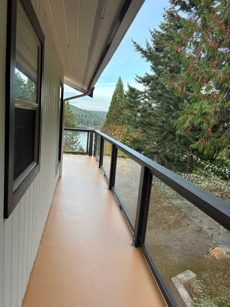 After: Side deck walkway with freshly coated floor, glass railing, and view of lake and trees, Souther Salt Spring. Isabella Point / Roland Rd, BC