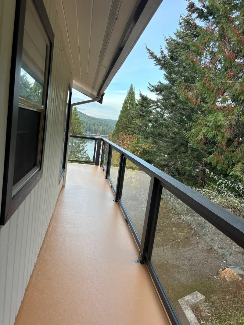After: Side deck walkway with freshly coated floor, glass railing, and view of lake and trees, Souther Salt Spring. Isabella Point / Roland Rd, BC