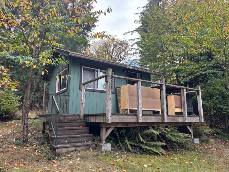 Before: Rear view of small green cabin with deck, railing, and window, Souther Salt Spring. Isabella Point / Roland Rd, BC