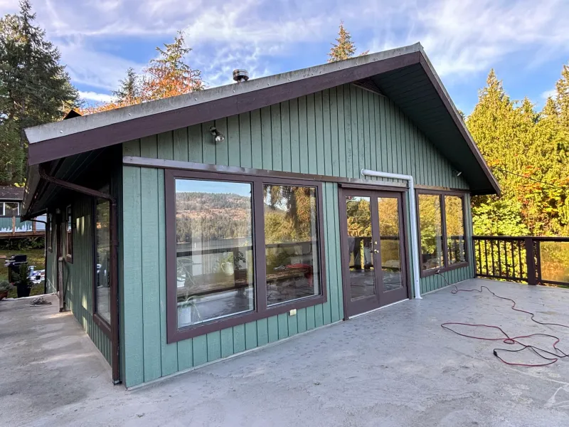 Before: Rear elevation of house with large windows, french doors, green siding, and brown trim, Souther Salt Spring. Isabella Point / Roland Rd, BC