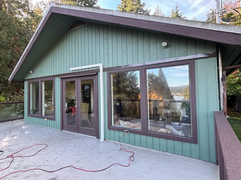 Before: Rear elevation of house with large windows, french doors, green siding, and brown trim, Souther Salt Spring. Isabella Point / Roland Rd, BC