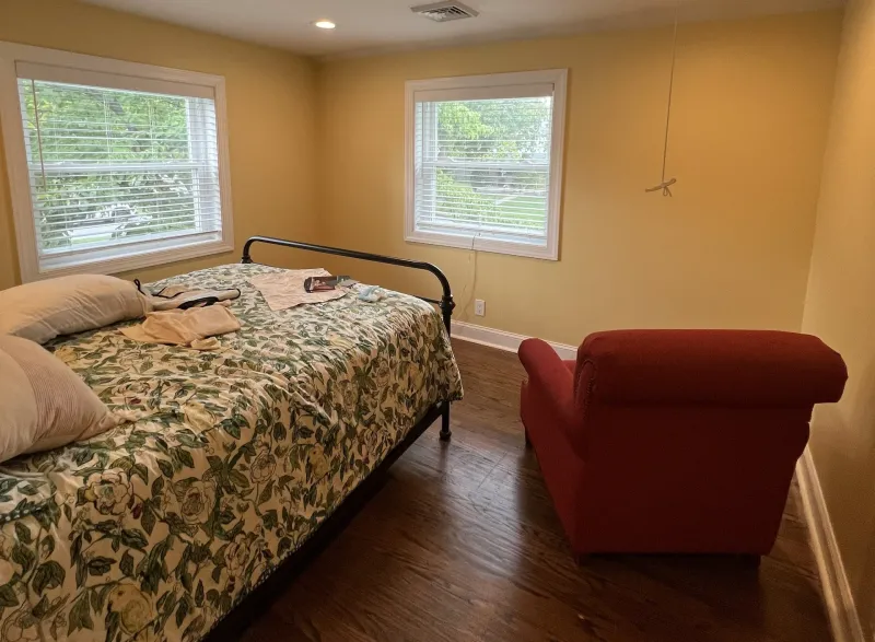 After: Bedroom with yellow walls, white trim, two windows, and flooring after painting, Springfield, PA