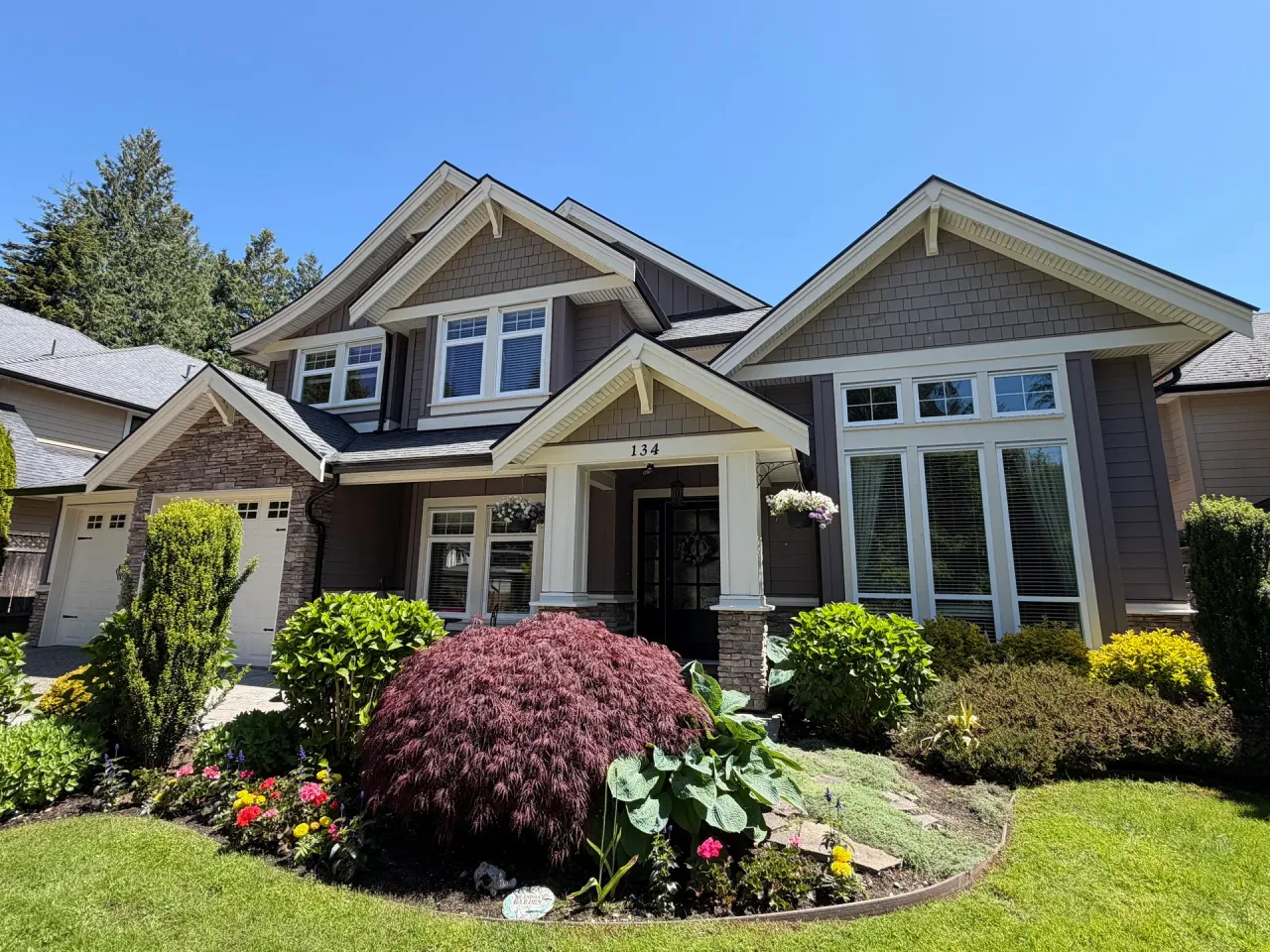 After: Front of two-story house with covered entry, bay window, gable roof lines, and landscaped garden beds, Tsawwassen, Delta, BC