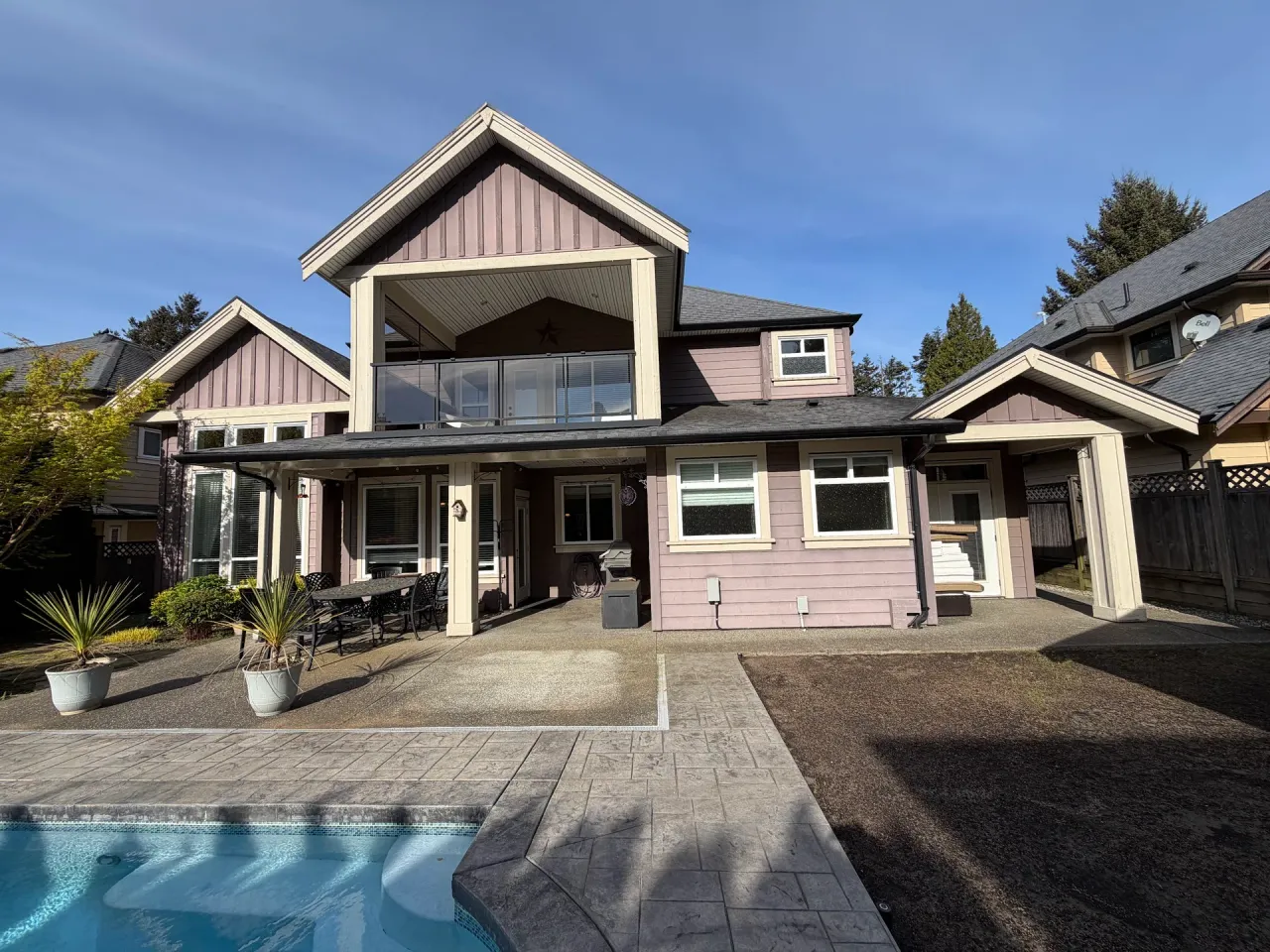 Before: Rear of two-story house with upper balcony, covered patio, and multiple windows overlooking a pool, Tsawwassen, Delta, BC