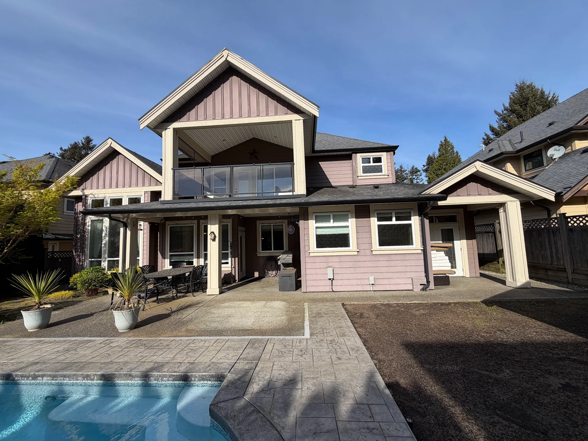 Before: Rear of two-story house with upper balcony, covered patio, and multiple windows overlooking a pool, Tsawwassen, Delta, BC