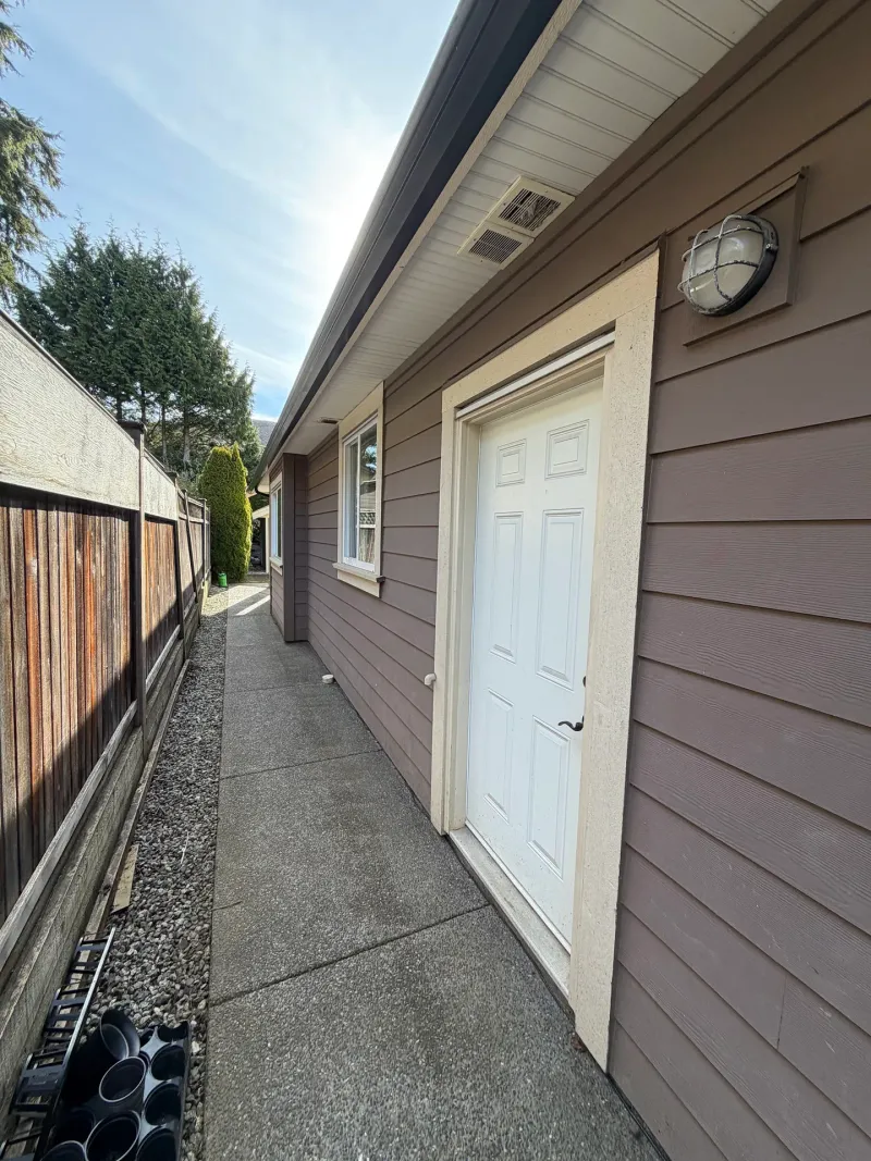 Before: Narrow side walkway alongside house with single door, small window, and round wall light fixture, Tsawwassen, Delta, BC