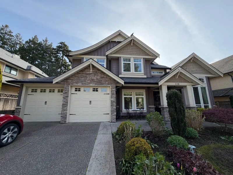 Before: Front of two-story house with double garage doors, stone accents, and covered entry, Tsawwassen, Delta, BC