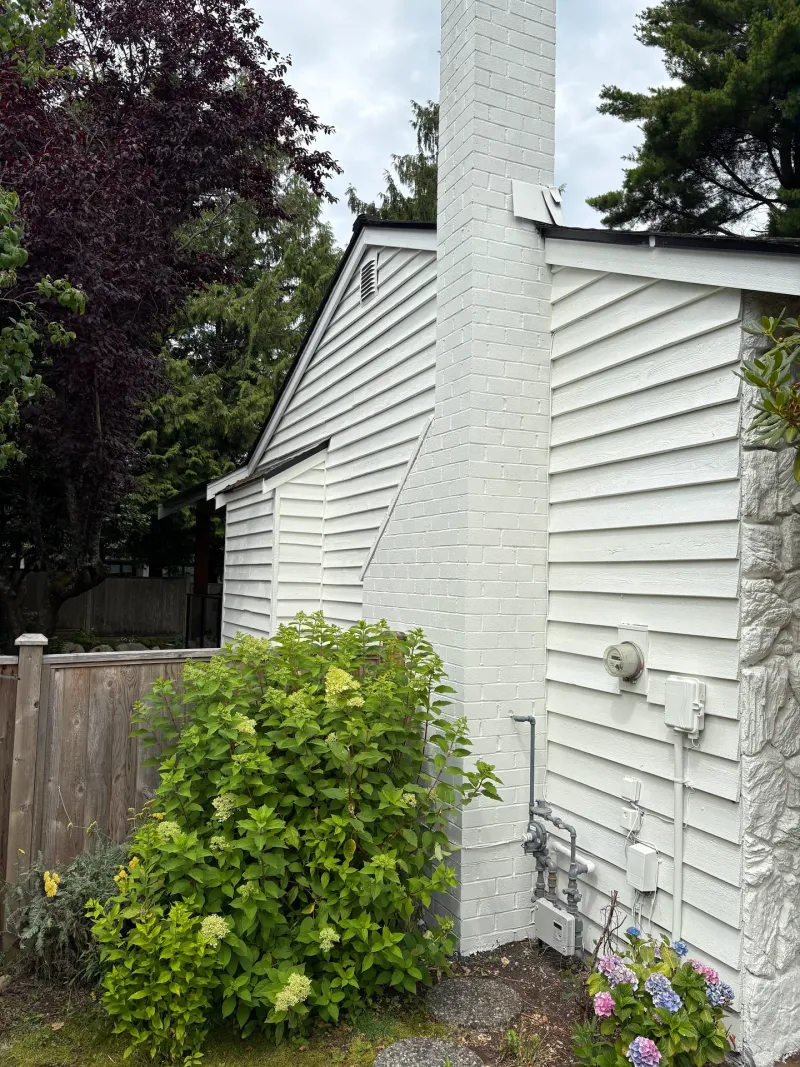 After: Side elevation of house with white siding, painted chimney and gable vent after painting, Tsawwassen, Delta, BC