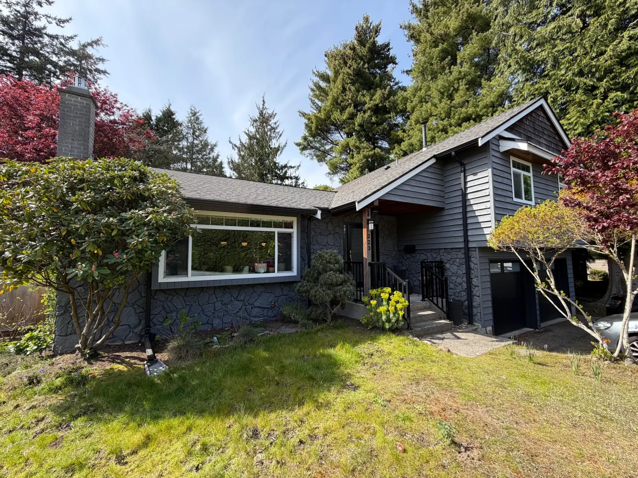 Before: Front elevation of house with dark siding, stone base, entry door and attached garage before painting, Tsawwassen, Delta, BC