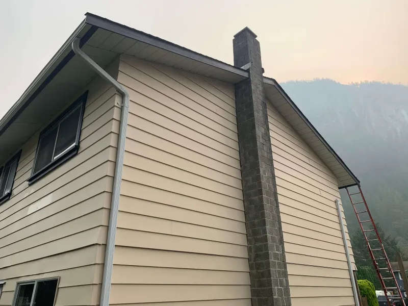 After: Side elevation of house with chimney, gutters, and freshly painted siding, - Valley Cliff, Squamish, BC