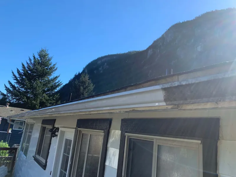 Before: Close view of roofline and eaves along the back of the house with mountain in background, - Valley Cliff, Squamish, BC