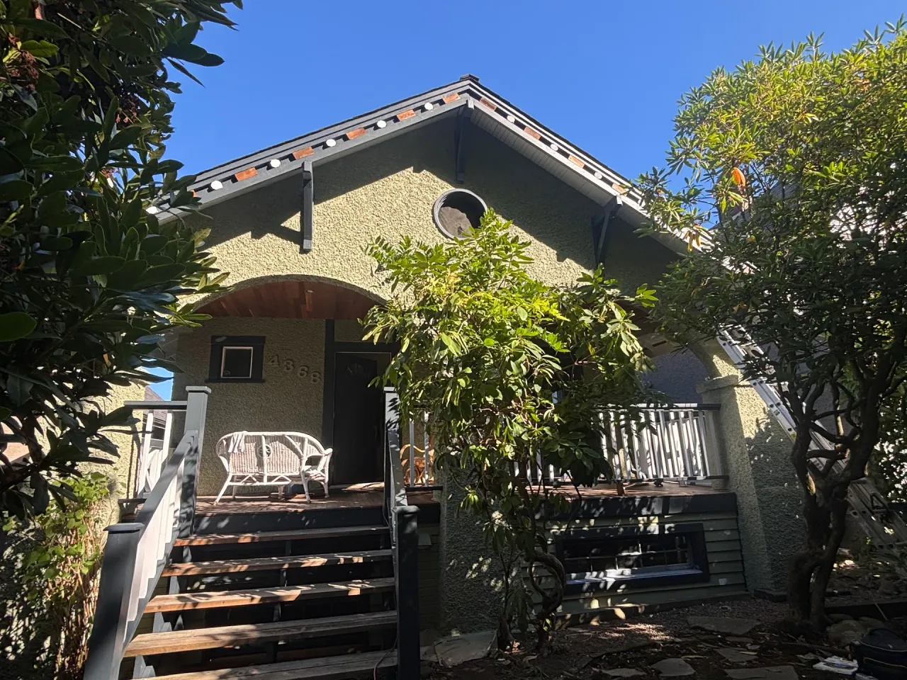 After: Front elevation of repainted house with arched porch entry, stairs, and deck railing, Vancouver, West Vancouver, BC
