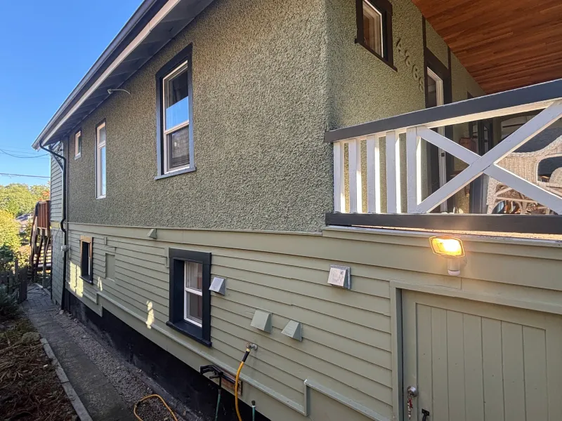After: Side elevation of house showing upper wall, windows, deck railing and lower siding freshly painted, Vancouver, West Vancouver, BC