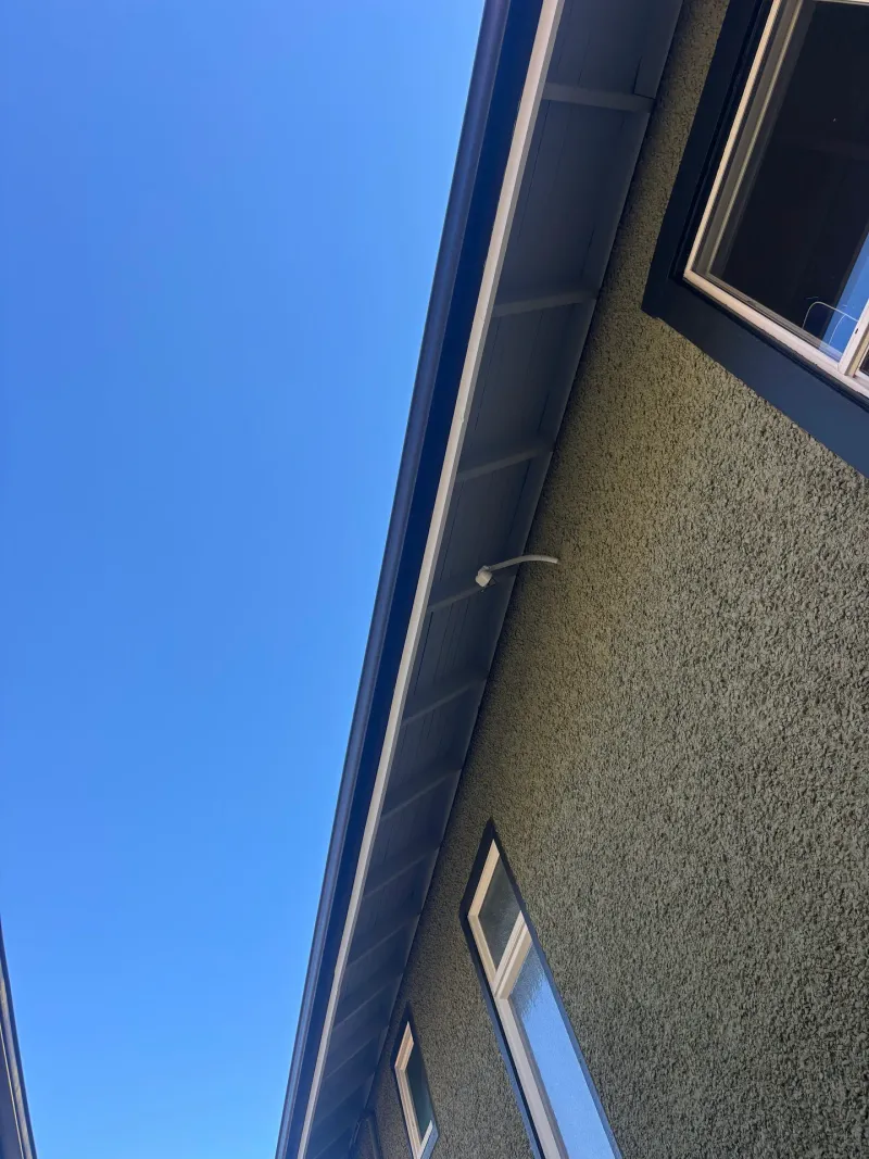 After: Upward angle view of eave, gutter and wall surface against sky, Vancouver, West Vancouver, BC