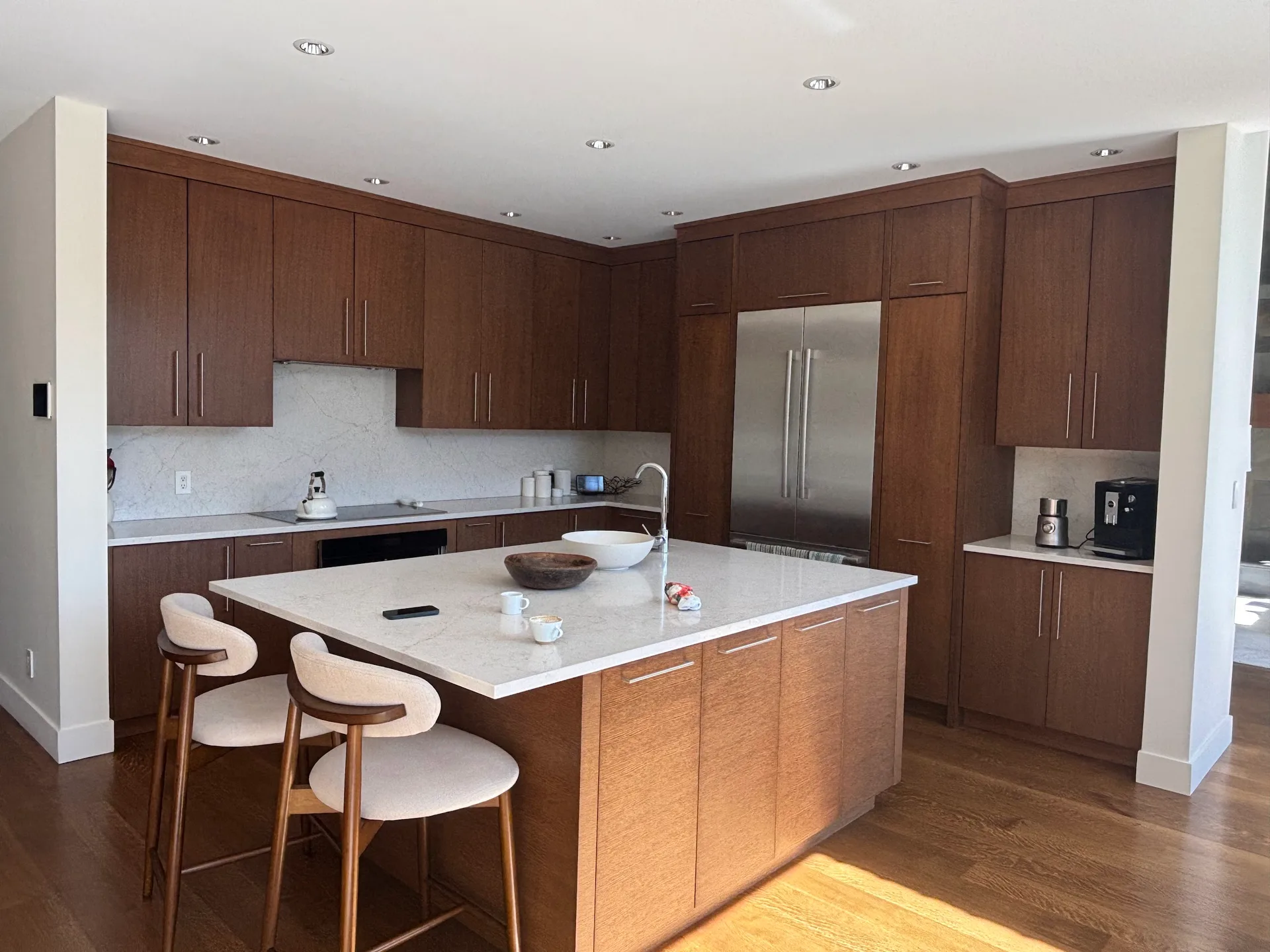 Before: Wide kitchen view with cabinetry, island seating, and stainless refrigerator, Whistler, BC